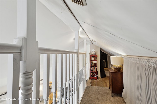 corridor featuring light carpet and vaulted ceiling