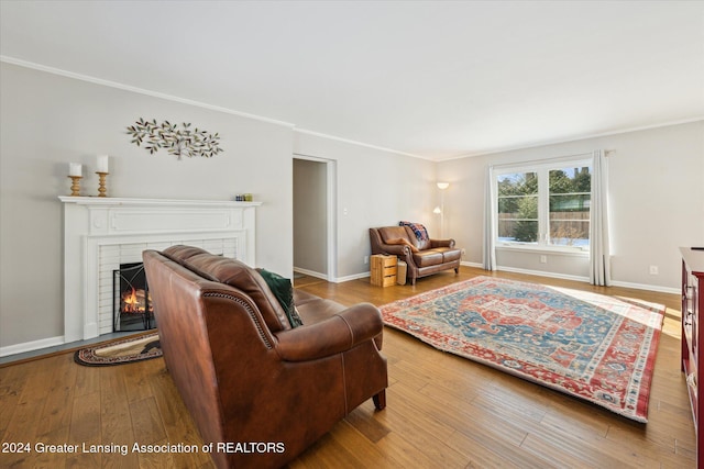 living room featuring hardwood / wood-style floors, a brick fireplace, and crown molding