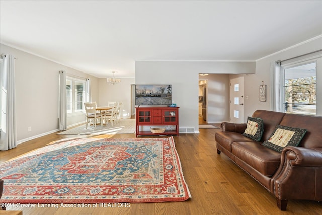 living room featuring hardwood / wood-style flooring, a notable chandelier, and crown molding