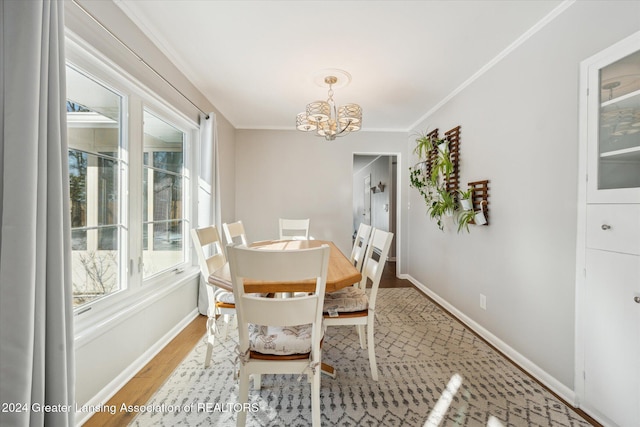 dining area featuring light wood-type flooring, ornamental molding, and an inviting chandelier