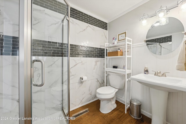 bathroom with hardwood / wood-style floors, toilet, a shower with door, and sink