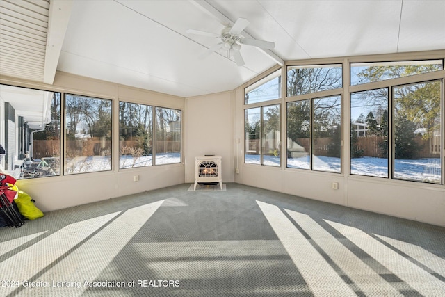 sunroom with a wood stove, ceiling fan, heating unit, and vaulted ceiling with beams