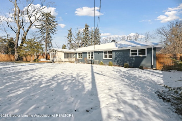 snow covered house featuring central air condition unit and a sunroom