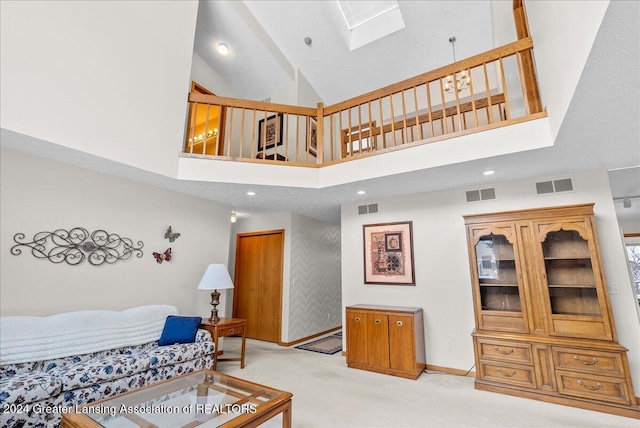 carpeted living room with a high ceiling and a skylight