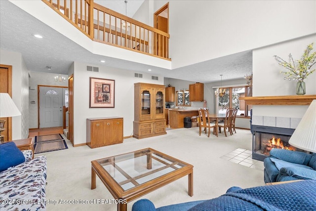 living room with a high ceiling, a tiled fireplace, and light colored carpet