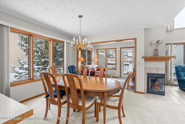 dining space featuring a tiled fireplace, light colored carpet, a textured ceiling, and a chandelier