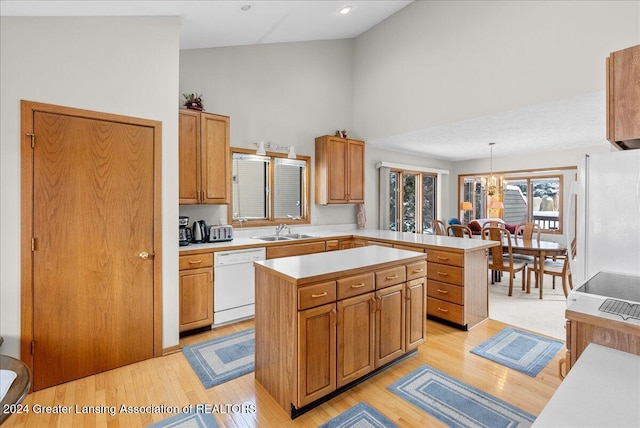 kitchen featuring white appliances, a center island, decorative light fixtures, and kitchen peninsula