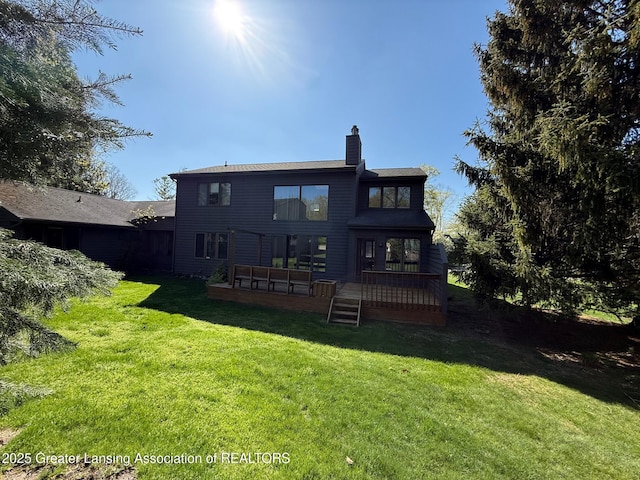 rear view of house featuring a chimney, a wooden deck, and a yard