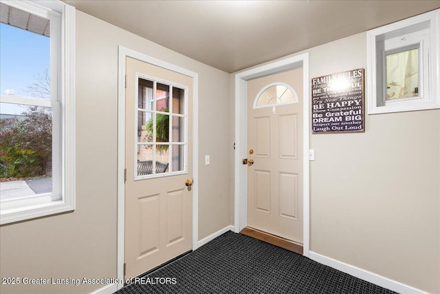 doorway to outside featuring dark colored carpet and a healthy amount of sunlight