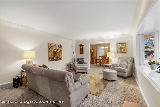 carpeted living room with a healthy amount of sunlight and a notable chandelier