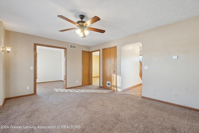 unfurnished room with a textured ceiling, ceiling fan, and light carpet