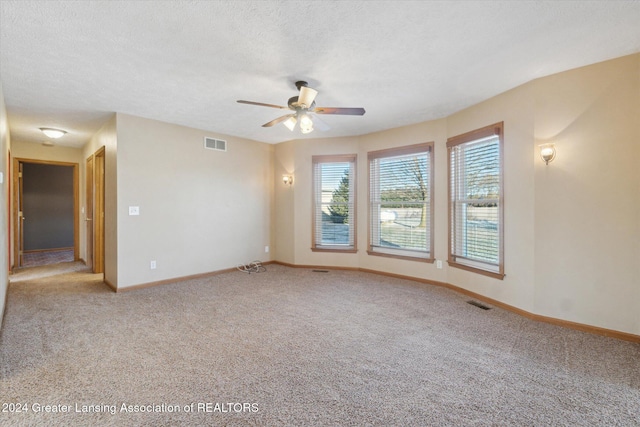 spare room featuring ceiling fan, light carpet, and a textured ceiling