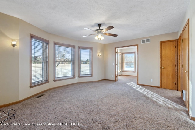 carpeted spare room featuring a textured ceiling and ceiling fan