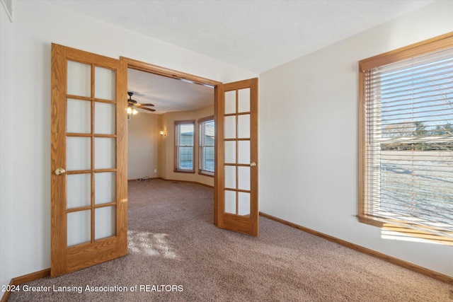 carpeted spare room with ceiling fan and french doors