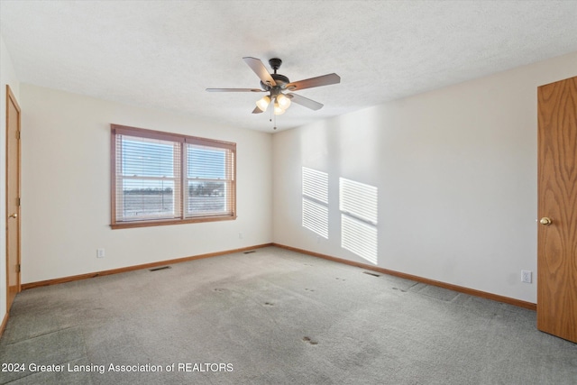 carpeted spare room with ceiling fan and a textured ceiling