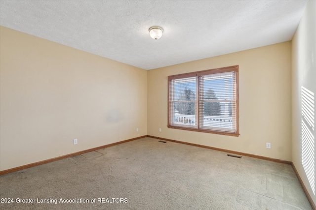 carpeted empty room featuring a textured ceiling