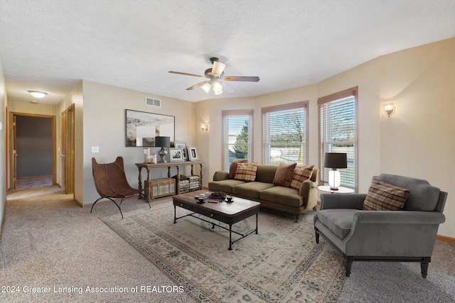 living room featuring light carpet, ceiling fan, and a textured ceiling