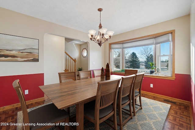 dining room with a chandelier, dark parquet flooring, a textured ceiling, and a wealth of natural light