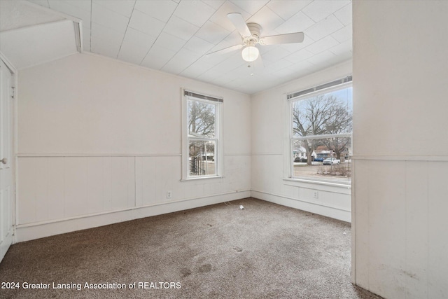 carpeted empty room featuring ceiling fan, a wealth of natural light, and vaulted ceiling