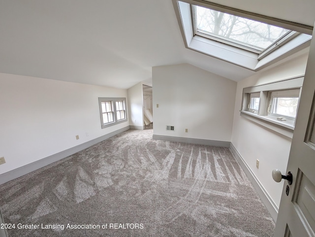 additional living space with lofted ceiling with skylight and carpet floors