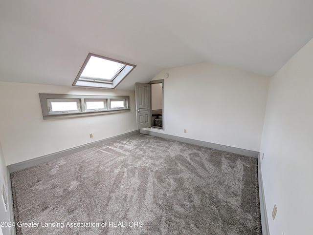 additional living space with carpet flooring and lofted ceiling with skylight