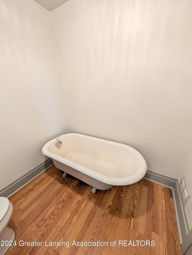 bathroom with toilet, wood-type flooring, and a bathing tub