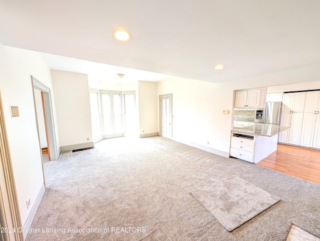 unfurnished living room with light colored carpet