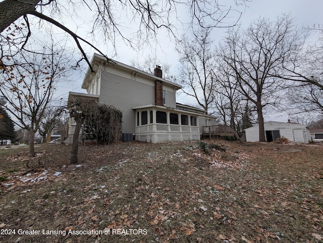 back of property with a garage, a deck, a sunroom, and an outdoor structure