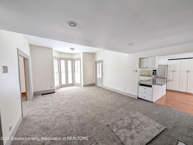 unfurnished living room featuring light colored carpet