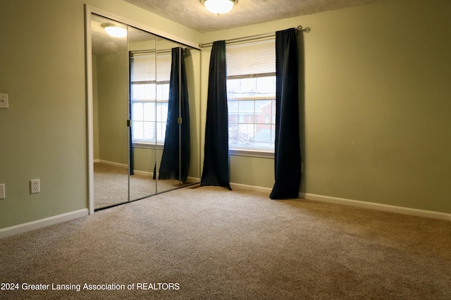 unfurnished bedroom featuring carpet flooring, a textured ceiling, and a closet