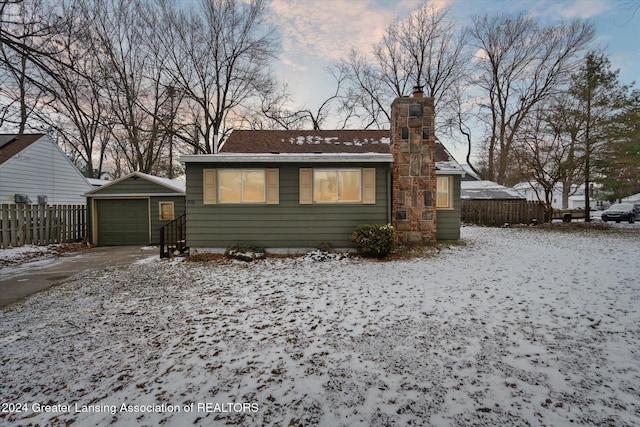 snow covered back of property with a garage and an outbuilding