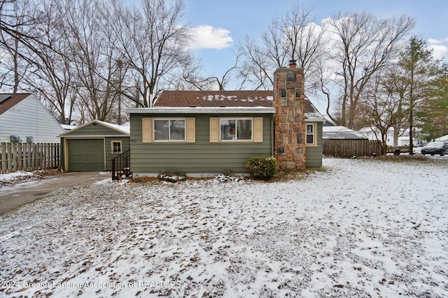 snow covered house with an outbuilding and a garage