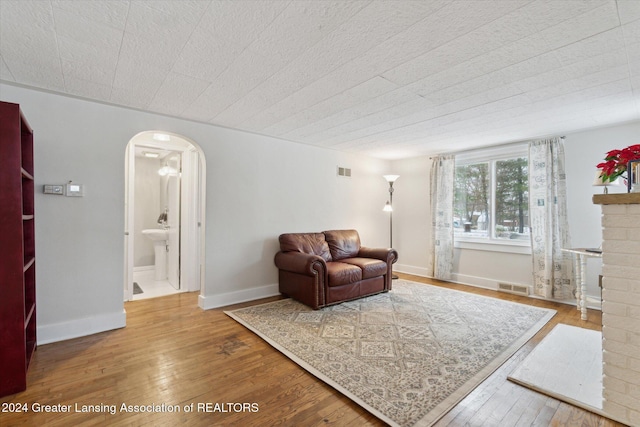 living room with wood-type flooring and a brick fireplace