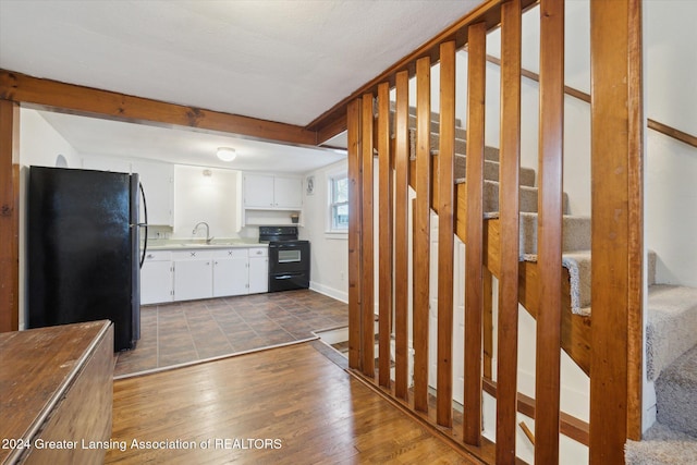 kitchen with dark wood-type flooring, sink, black appliances, beamed ceiling, and white cabinetry