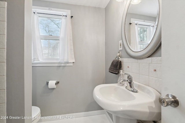 bathroom with decorative backsplash, toilet, plenty of natural light, and sink