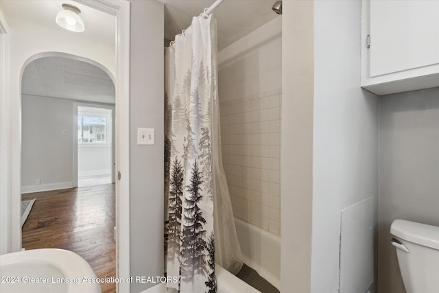 bathroom featuring shower / bath combination with curtain, toilet, and hardwood / wood-style floors