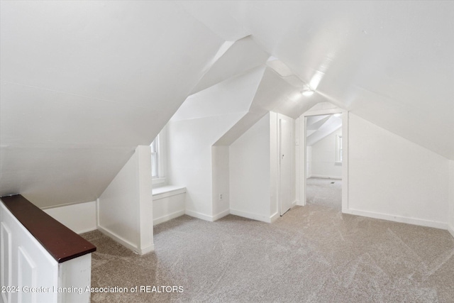 bonus room with light colored carpet and vaulted ceiling