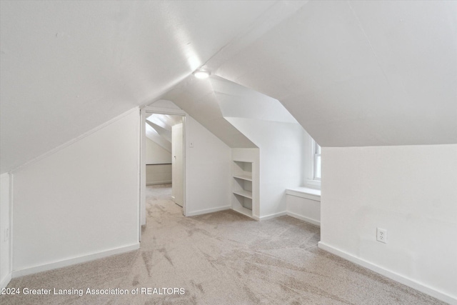 additional living space featuring light colored carpet and lofted ceiling