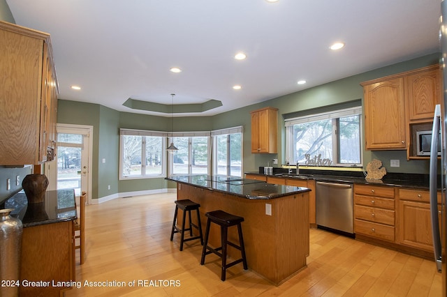 kitchen with a kitchen breakfast bar, a center island, dark stone counters, light hardwood / wood-style flooring, and stainless steel dishwasher