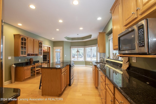 kitchen with a breakfast bar, a kitchen island, light wood-type flooring, appliances with stainless steel finishes, and sink