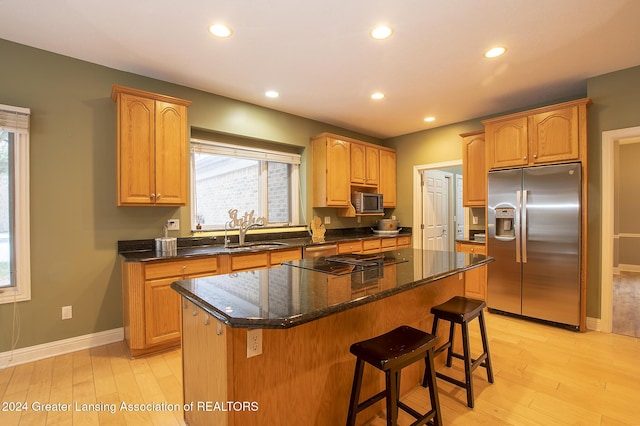 kitchen featuring sink, stainless steel appliances, light hardwood / wood-style flooring, and a kitchen island