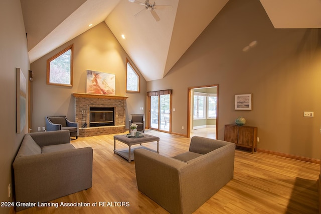 living room featuring high vaulted ceiling, a fireplace, light wood-type flooring, and ceiling fan