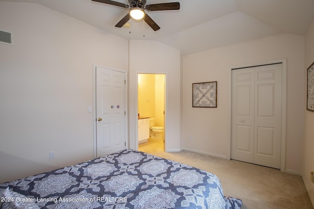 carpeted bedroom featuring lofted ceiling, ensuite bath, ceiling fan, and a closet