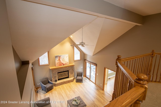 living room with a brick fireplace, hardwood / wood-style flooring, vaulted ceiling with beams, and plenty of natural light