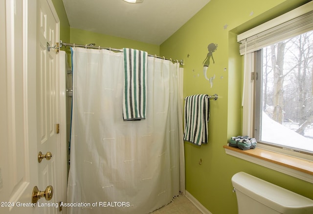 bathroom with curtained shower, tile patterned floors, and toilet