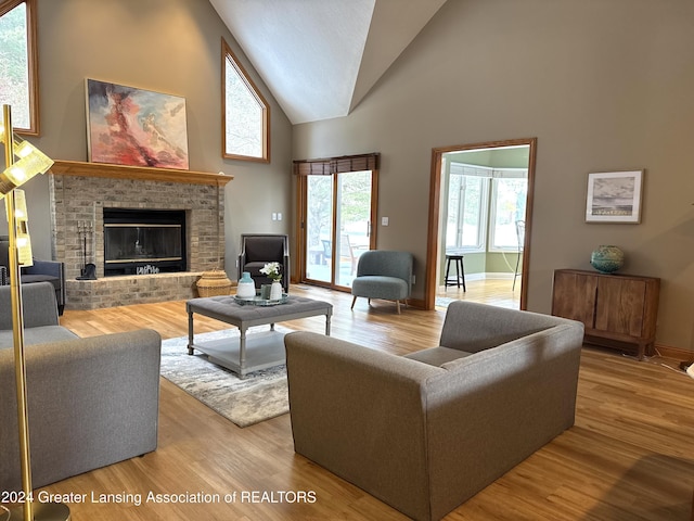 living room with high vaulted ceiling, a brick fireplace, and wood-type flooring