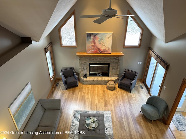 living room with ceiling fan, high vaulted ceiling, a fireplace, and hardwood / wood-style flooring