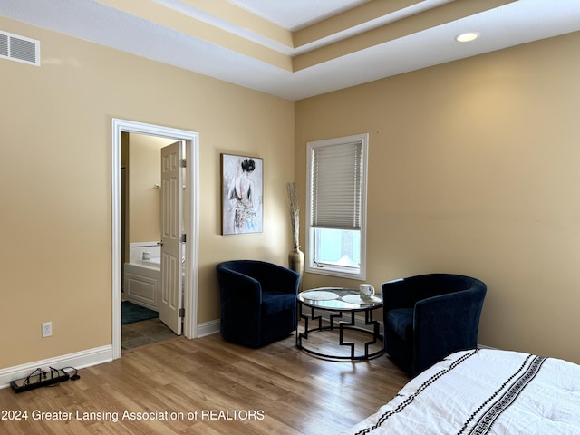 bedroom with ensuite bath and hardwood / wood-style floors