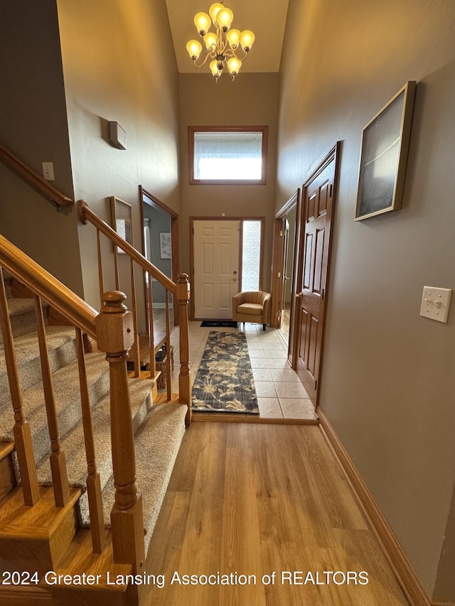 entryway with a high ceiling, an inviting chandelier, and light hardwood / wood-style flooring