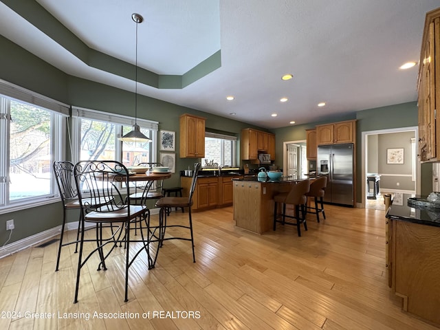 dining space featuring light hardwood / wood-style flooring and a tray ceiling